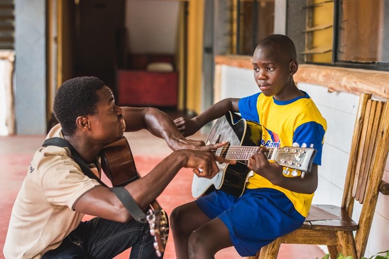A teen learning guitar with a mentor